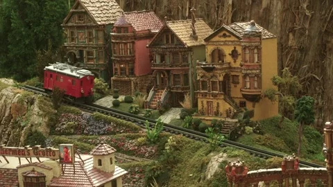 Close Up Shot Of A Toy Train Set With A Red Electric Caboose In A Replica Town Видео 328399674