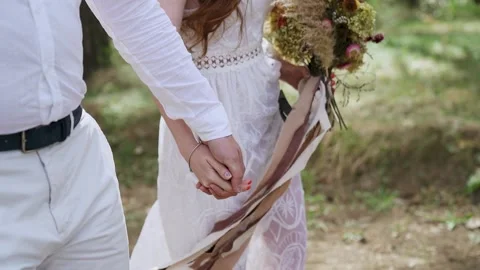 Close up shot with tracking of young couple holding hands and walking in forest. Stock Footage 205225959