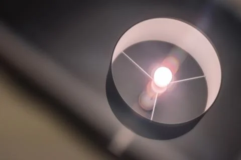 A close-up shot of a turned on lamp reflected in the display of a smartphone Stock Photos