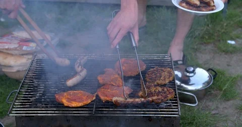 Close up shot turning of meat at a coal fired barbecue Stock Footage 111135660
