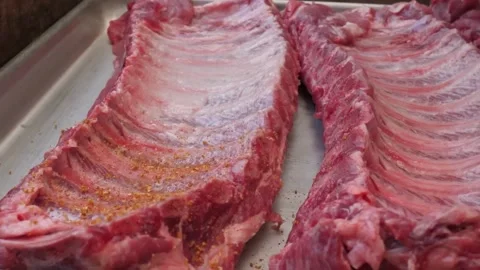 Close-up Shot of Two Fresh Raw Racks of Pork Spare Ribs on a Stainless Steel Tra Stock Footage 338212154