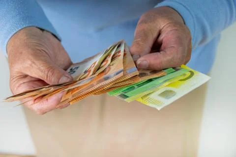 A close-up shot of two hands holding a stack of euro bills. The hands are l.. Stock Photos