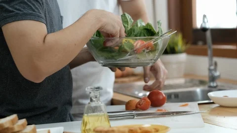 Close up shot of two man help to prepare vegetable salad in the kitchen Stock-Footage 125814716