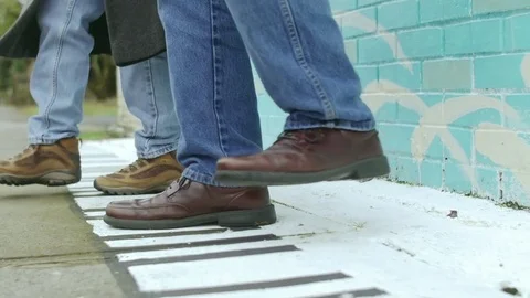 Close up shot of two people playing around with a piano painting on a road Stock Footage 83035318