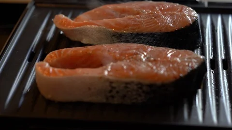 Close up shot of two salmon steaks on the grill one side of peace not grilled Stock Footage 114001305