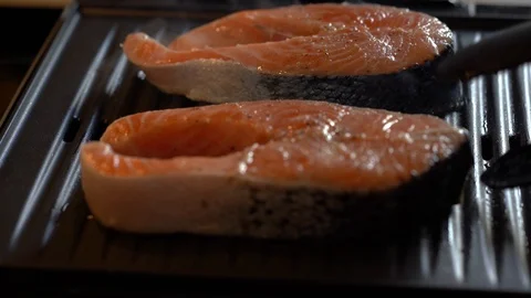Close up shot of two salmon steaks on the grill as chef flips with tongs Stock Footage 114001315
