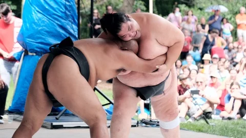 Close shot of two sumo wrestlers fighting while throwing one another. Slomo Vidéo 115668945