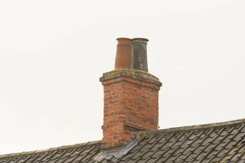 Close-up shot of two weathered chimney pots on a brick chimney stack with a Stock Photos