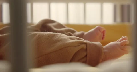 Close-up shot of unrecognizable infant lying in crib, activly moving legs. Macro Video stock 147932049