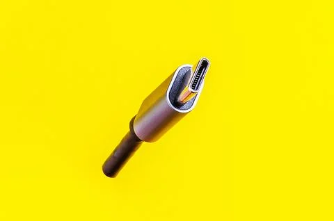 This close-up shot of a USB-C cable against a vibrant yellow backdrop is id.. Stock Photos
