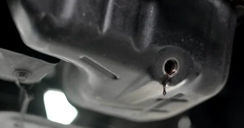 Close-up shot of used engine oil dripping from the drain plug under a vehicle. Stock Footage 311370801