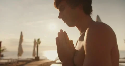 Close-up shot: a view of a calm guy meditating on the beach at sunrise. Morning Stock Footage 249435877