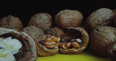 Close-up Shot of Walnuts which lie on a yellow table against a black background Stock Footage 167853065