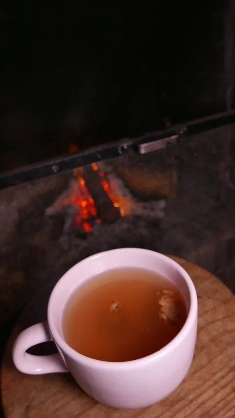 Close-up shot of a warm cup of ginger tea with honey on a table by the fireplace Stock Footage 337799808
