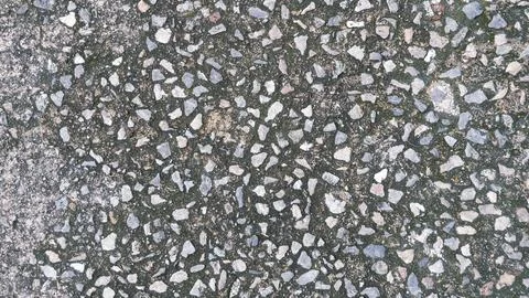 Close-up shot of a weathered concrete surface embedded with small rough stones. Stock Photos