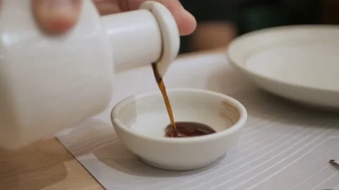Close up shot while pouring soy sauce into sauce plate for sashimi sushi japa Stock Footage 218360443