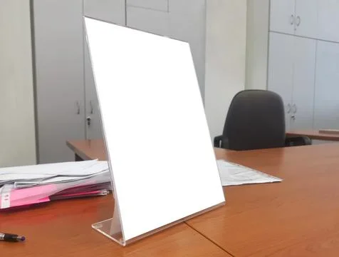 Close up shot of a white empty advertising board standing on a brown office desk Stock Photos