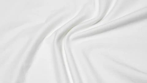 Close up shot of a white fabric surface with soft folds and a subtle texture. Stock Photos