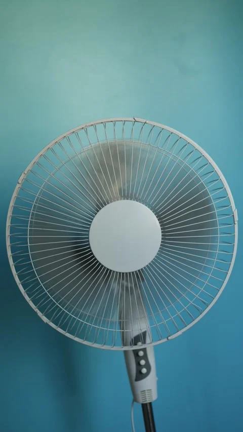 Close-up shot of a white oscillating fan spinning against a blue background Stock Footage 340266194