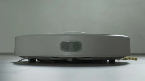 Close up shot of white robot vacuum cleaner cleans the floor from debris Stock Footage 253504731