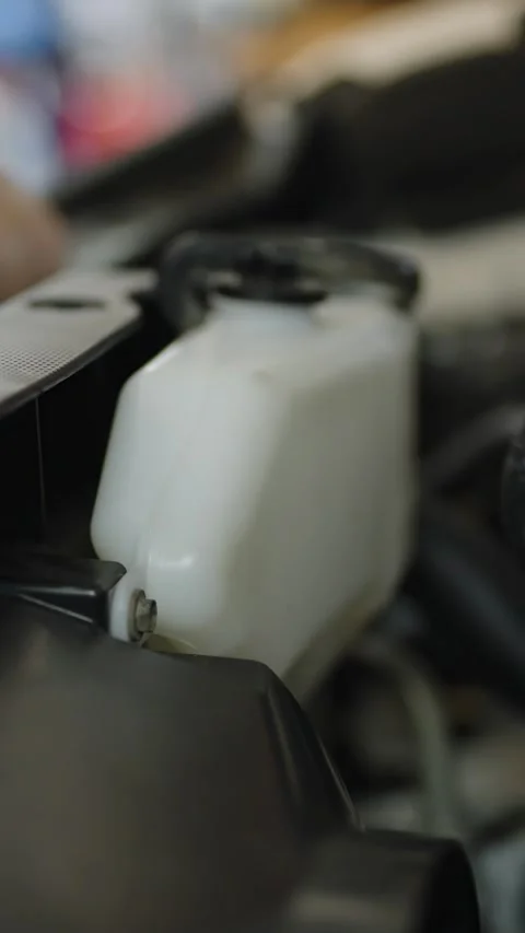 A close-up shot of a white translucent plastic coolant overflow tank inside 動画素材 336710529
