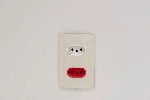 Close Up shot of a white wall plug with a Swiss and Brazilian standard socket Stock Photos