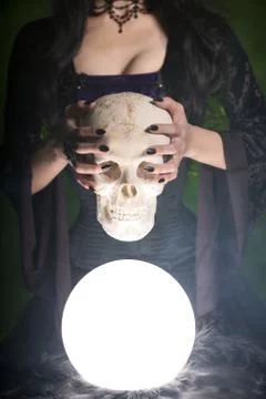 Close-up shot of a witch with long nails holding human skull Foto stock