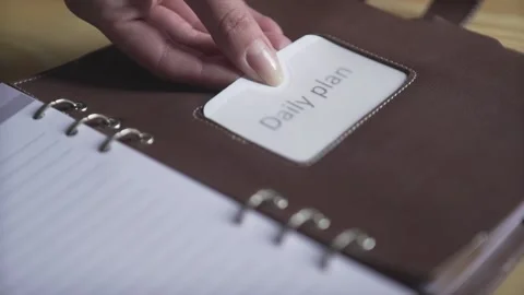 Close up shot of woman hands using sticker tag in brown leather bullet journal d Stock Footage 137539178