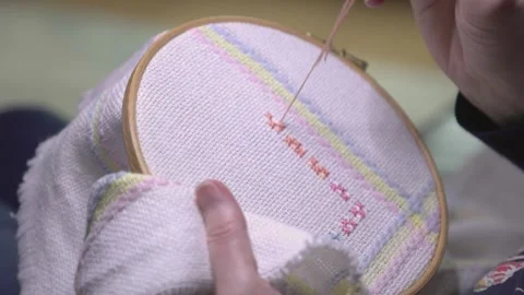 Close-up shot of a woman making patterns on a cross-stitch baby blanket Stock Footage 266156790