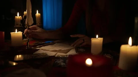 Close up shot of woman sitting on the table with many candles and tarot cards Stock Footage 247983370