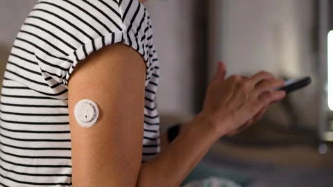 Close-up shot of a woman using a smartphone diabetes app to scan a continuo.. Stock Footage 344584095