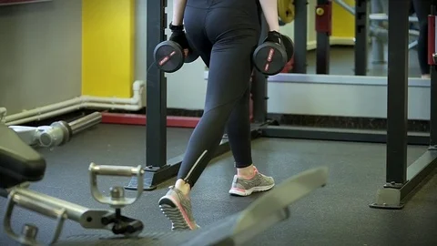 Close up shot of a woman who does warm-up squats with dumbbells. Stock Footage