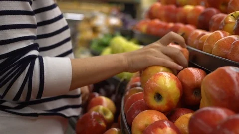 Close up shot of a woman's hand picking up a fresh organic red apple from a pile Stock Footage 89560737