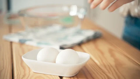 Close up shot of woman's hand picking chicken egg from a bowl Stock Footage 130043129