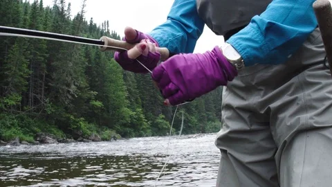 Close up shot of a woman's hand, as pulling back the line on a fly fishing Video stock 99852427