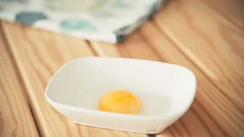 Close up shot of woman's hand putting an egg yolk from an eggshell to the bowl. Stock Footage 130043025