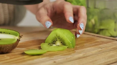 Close-up shot of womans hands cutting fresh peeled kiwi. Fruit for healthy Stock-Footage 150787744