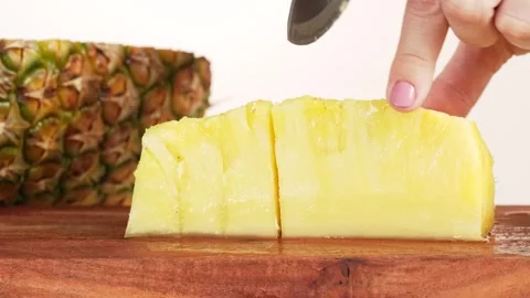 Close-up shot of womans hands cutting ripe pineapple into pieces with knife.. Stock Footage 314431552