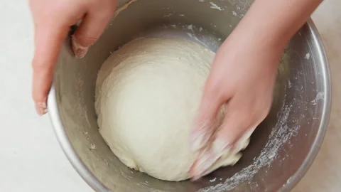 Close up shot of woman's hands kneading a dough in a stainless steel bowl. To Stock Footage 300095575