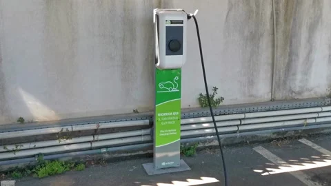 Close up shot of a woman's hands plugging in her electric car or EV at electric Stock Footage 204024087