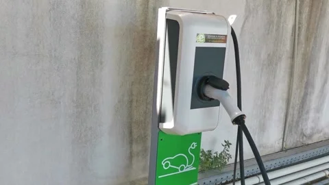 Close up shot of a woman's hands plugging in her electric car or EV at electric Stock Footage 204024111