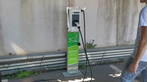 Close up shot of a woman's hands plugging in her electric car or EV at electric Stock Footage 204768158