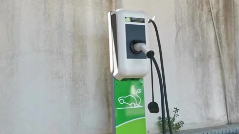 Close up shot of a woman's hands plugging in her electric car or EV at electric Stock Footage 205104945