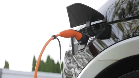 Close up shot of a woman's hands plugging in her electric car or EV at electric Stock Footage 272307403