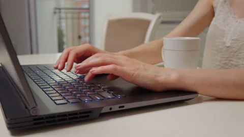 Close up shot of womans hands working on laptop and having a cup of tea nearby. Stock Footage 295815840