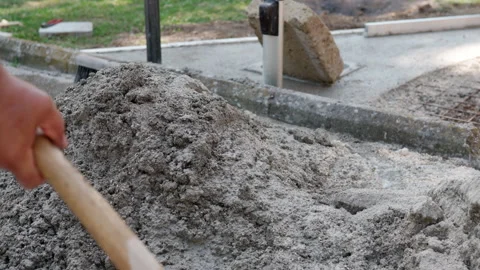 Close up shot of workman in dirty clothes mixing wet concrete with shovel Stock Footage 164596958