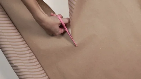Close up shot of the wrapping paper cutted by pink scissors in a woman's hand Stock Footage 98264249