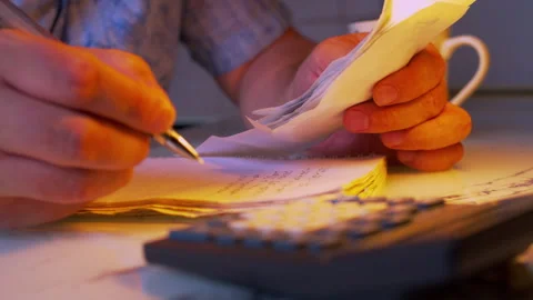 Close-up shot of writing down expense numbers from bills into a ledger book Video stock 336976579