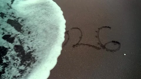 Close up shot of the year 2026 writen in black sand on a beach. Video stock 345584260