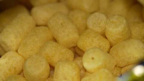 Close-up shot of yellow corn puffs inside an open bag. Video stock 342949415